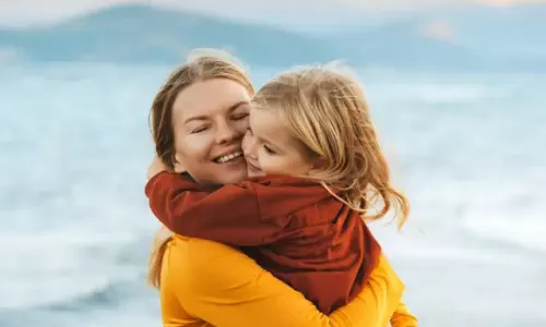 Eine Frau umarmt ihr Kind am Strand und genießt die gemeinsame Zeit, während sie von den Vorteilen des Betrieblichen Gesundheitsmanagements von Pluxee profitiert.