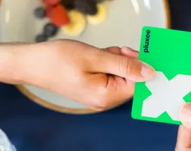 Zwei Menschen mit grüner Pluxee Card die überreicht wird.